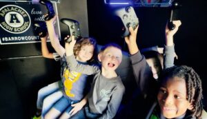 Children holding game controllers inside the Ultimate Mobile Gaming game truck