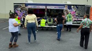 Adults participating in a group activity beside the Ultimate Mobile Gaming game truck at a corporate event
